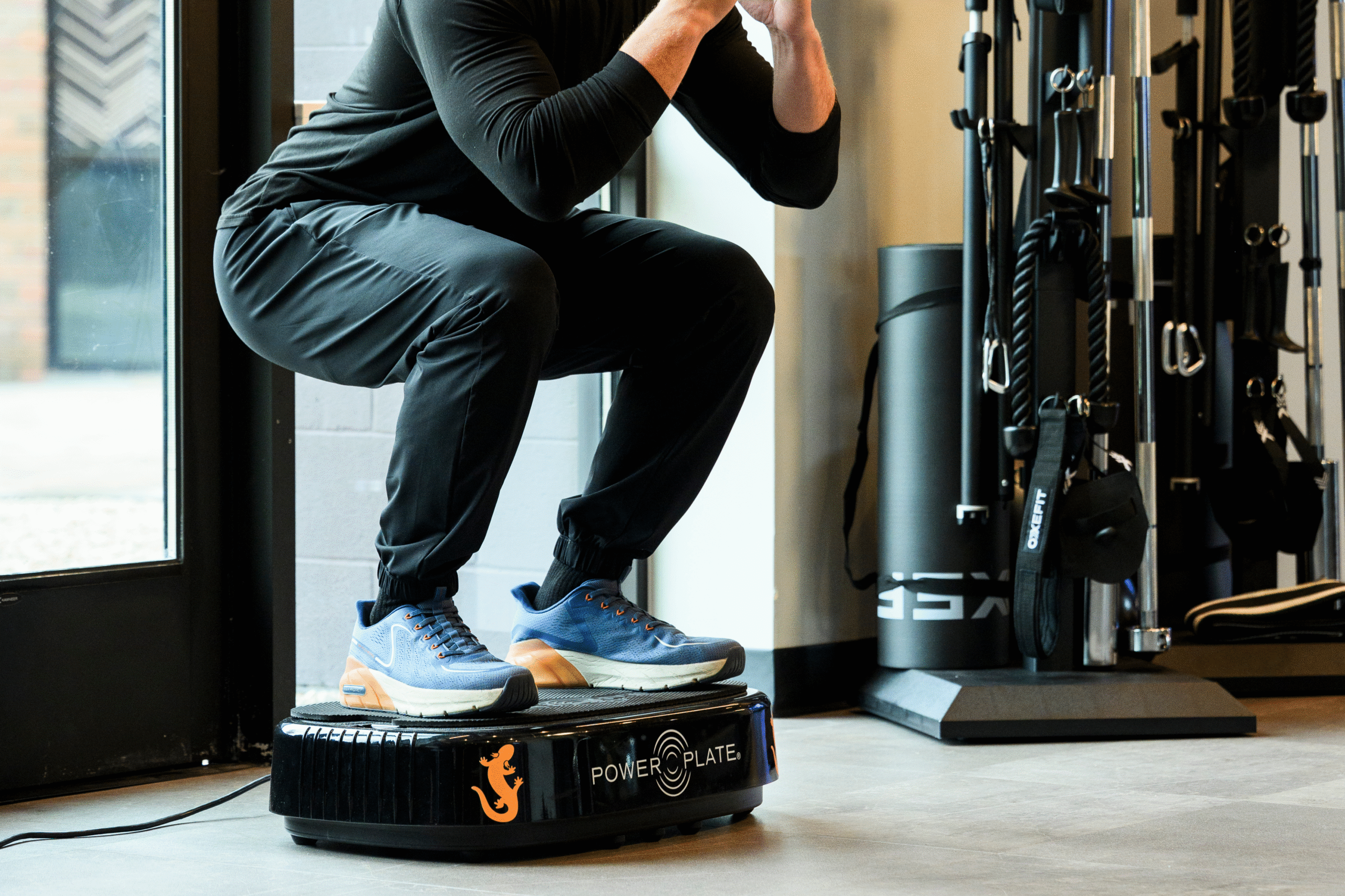 Man squatting on a PowerPlate® vibration platform.