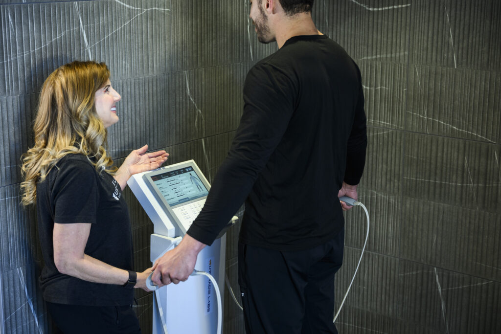Man standing on the Cell Health Analysis platform while a staff member guides him through the scan.
