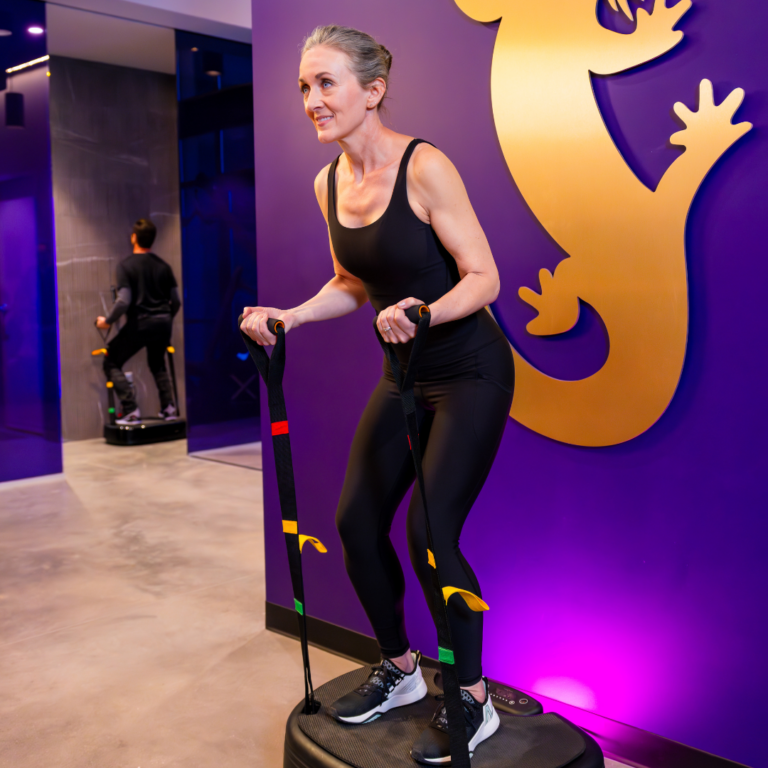 A woman in black athletic wear is working out on the Vibe Plate™ at Upgrade Labs.