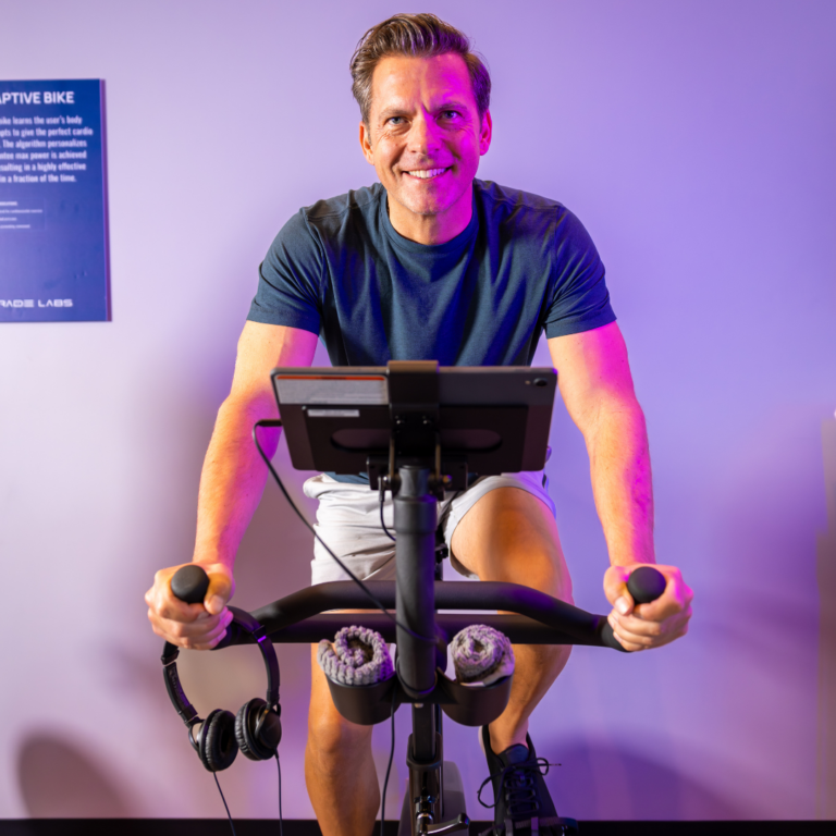 A man in athletic clothing is on the AI Adaptive Bike™ at Upgrade Labs