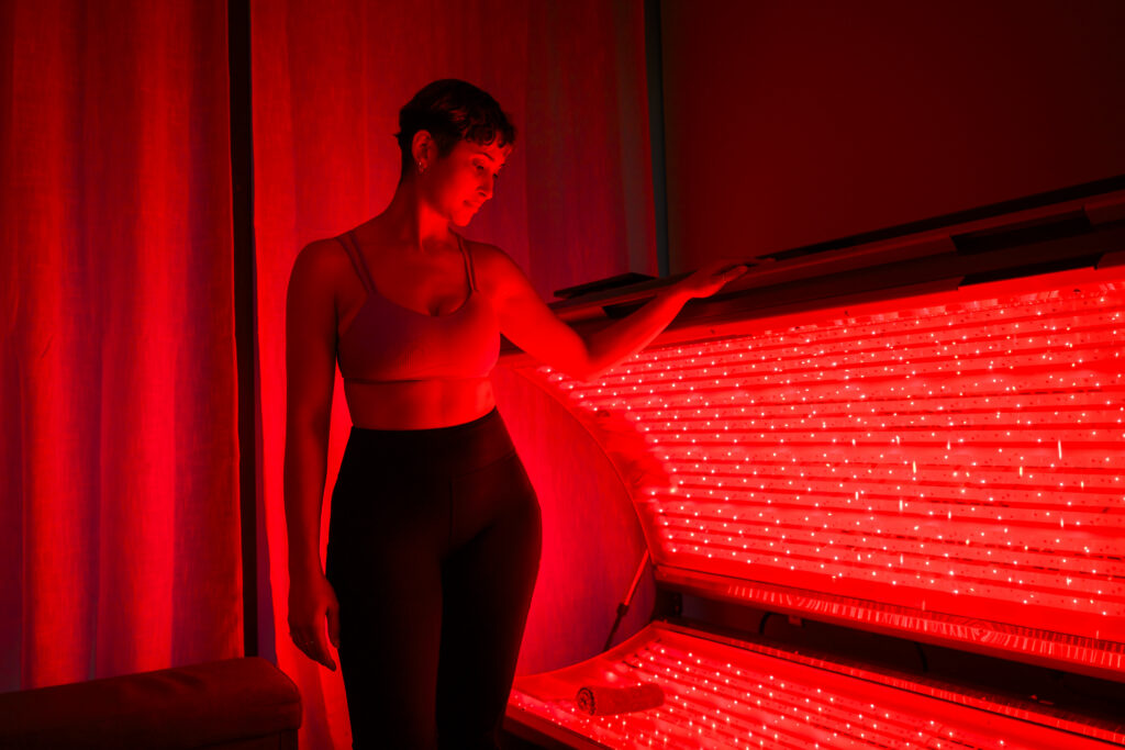 Woman opening and looking into the REDcharger red light therapy bed.