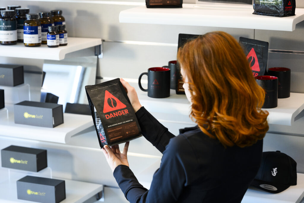 Woman holding and looking at a bag of Danger Coffee inside an Upgrade Labs center.