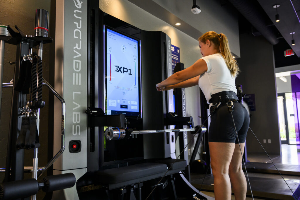 Woman performs a squat on the AI Strength Trainer, using adaptive resistance during a strength workout session.