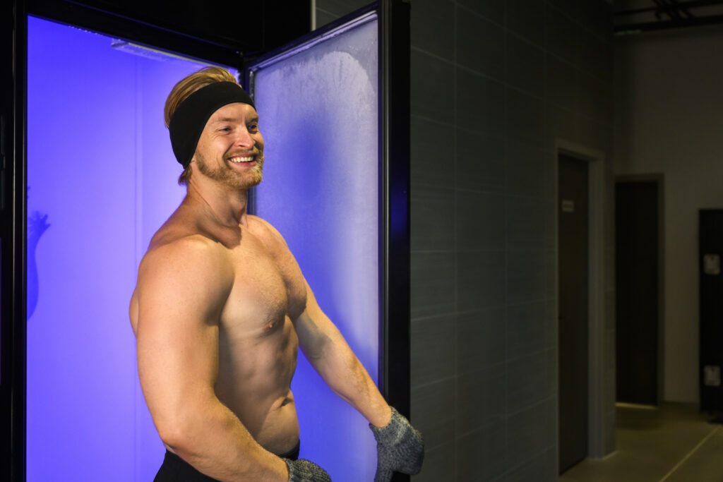 Man smiling while stepping out of a cryotherapy chamber.