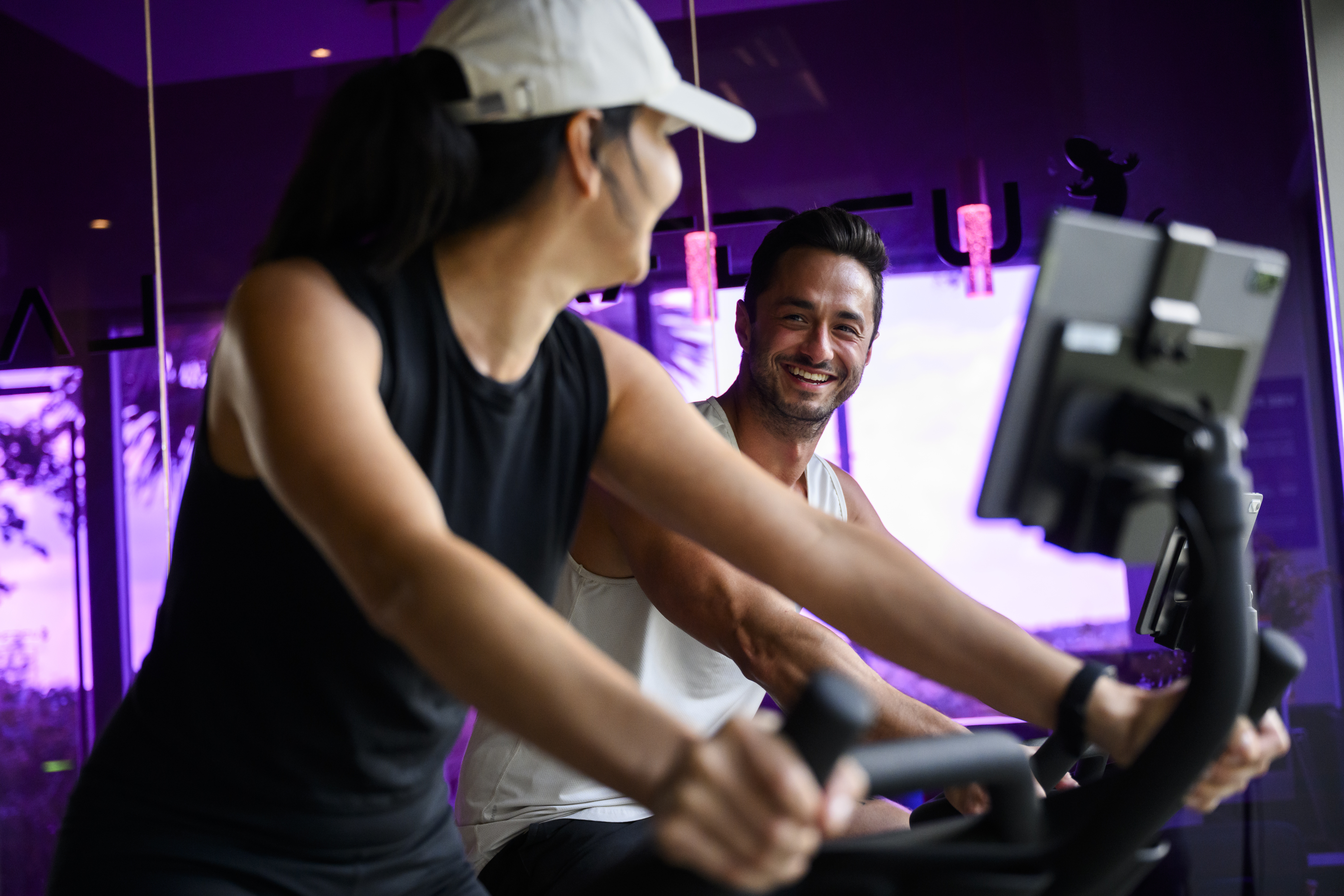 Two people riding the AI Adaptive Bike™ and looking at each other